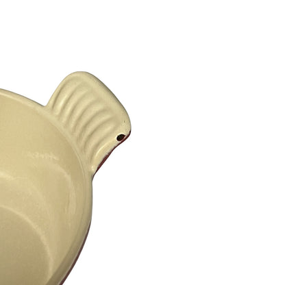 Close-up of a cream-colored ceramic handle with a ribbed texture and a small hole, shown on a plain white background.