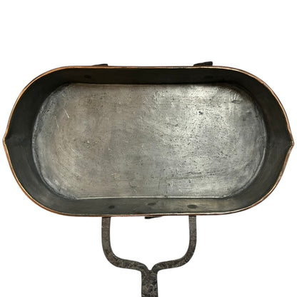 Close up of a copper roasting pan with a long handle on a white background