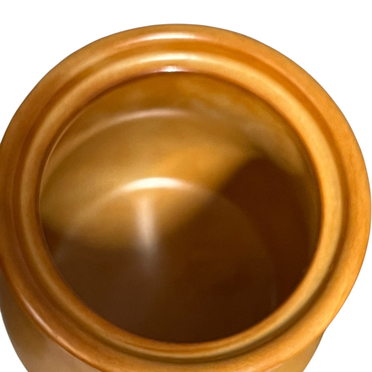 Close-up top-down view of a round kitchen jar showing warm golden-brown wood tones against a white background.