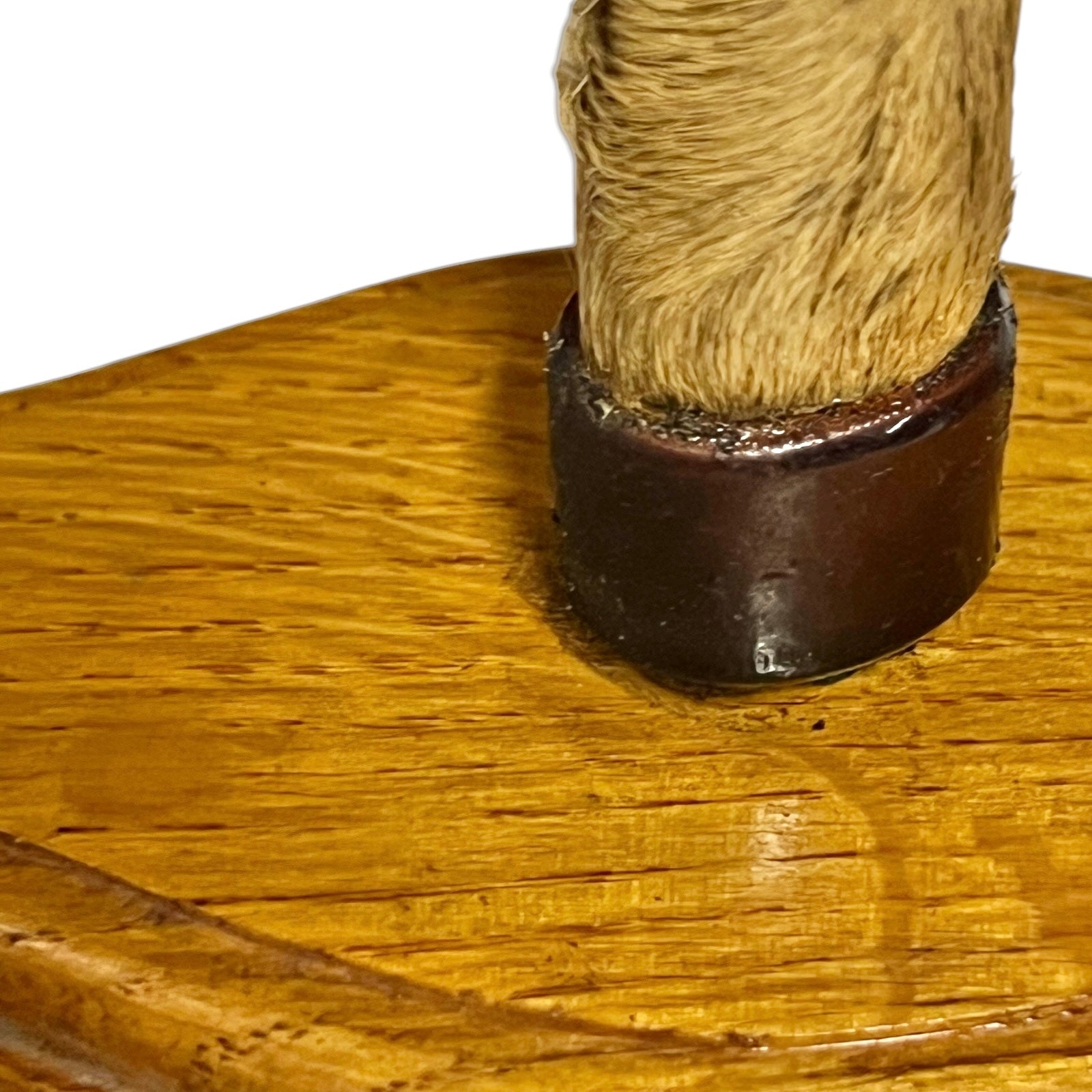 Close-up of a wooden display stand with a round polished wood base and a vertical post wrapped in tan fur, set against a plain white background.