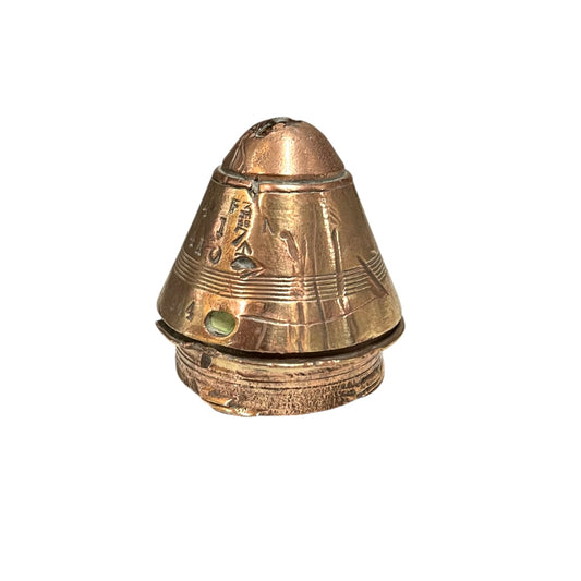 WW1 brass fuse paperweight with markings from use on a white background