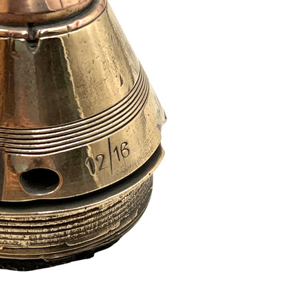 Close up of a polished British brass WW1 fuse or paperweight type 101 on a white background
