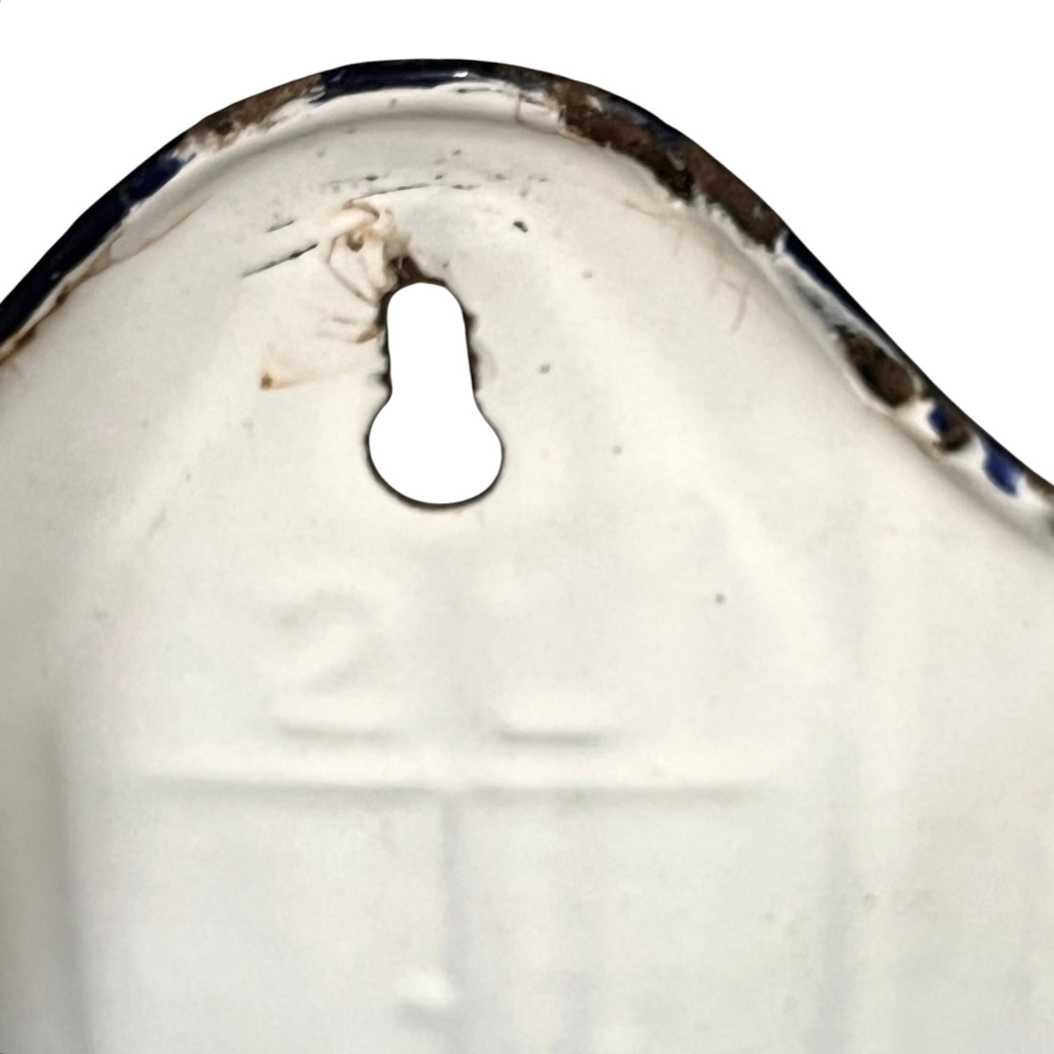 Close-up of a white enamel pot showing a keyhole cutout and some wear on the metal edge against a white background.