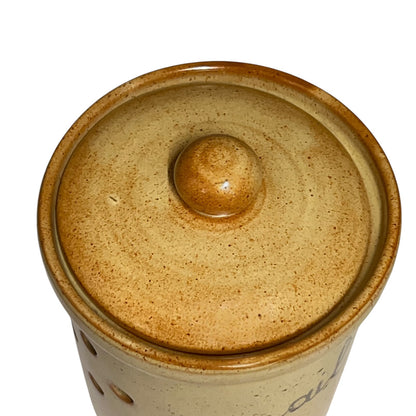 Close-up top view of a ceramic lidded container or jar with a rounded knob on top, shown on a plain white background.