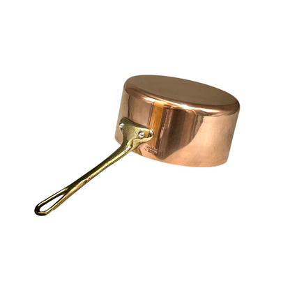 A small copper saucepan with a brass-colored handle, shown from a side angle against a plain white background.