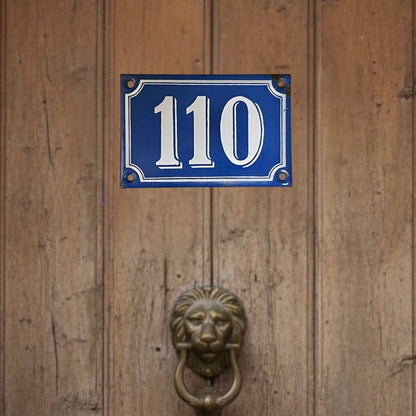 Wooden door with a blue house number sign and lion knocker.
