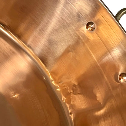 Close-up of a copper up cycled sink with brass handles on a white background.