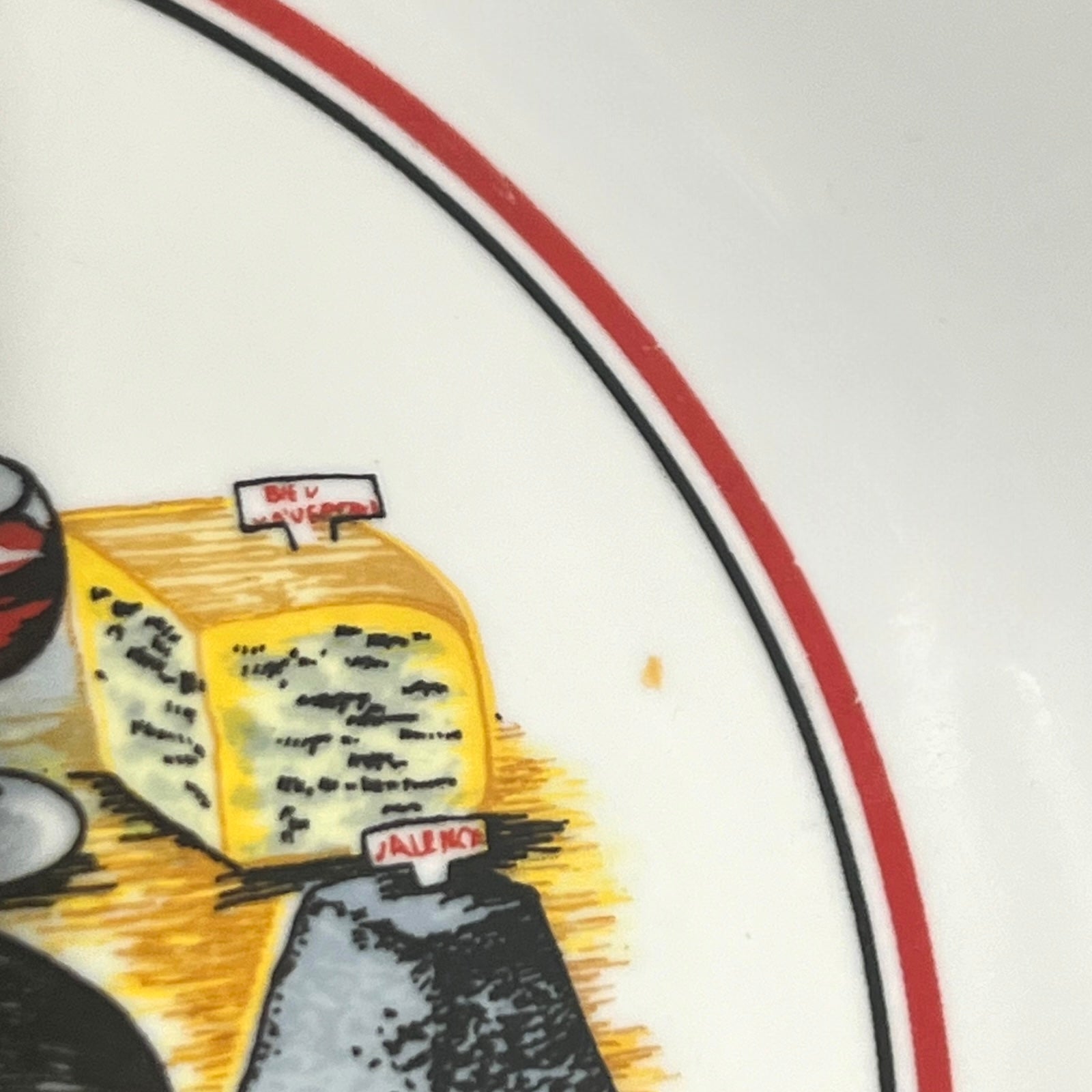 Close-up of a plate with a drawing of a wheel of cheese and a glass of wine.