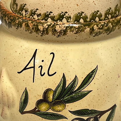 Decorative ceramic jar with olive design and 'Ail' inscription on a white background