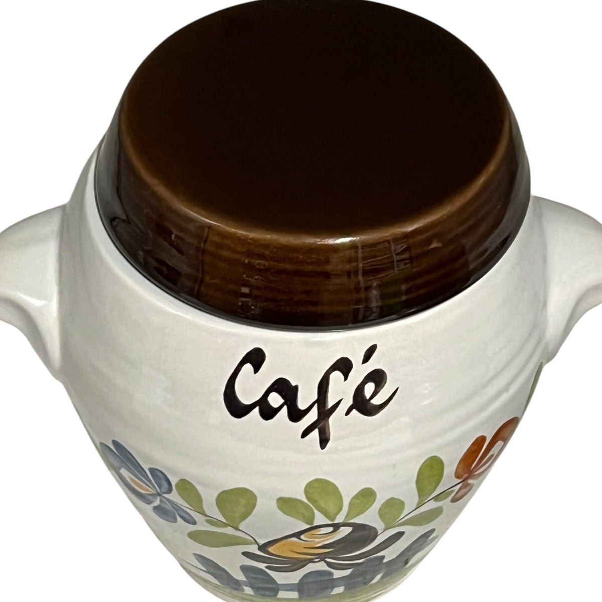 A white ceramic coffee cup or small canister with a dark brown lid, featuring the word 'Café' in black script and a floral pattern near the bottom.