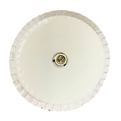 A round, off-white ceiling light fixture with a fluted or scalloped outer rim and a central metal socket, shown against a plain white background.