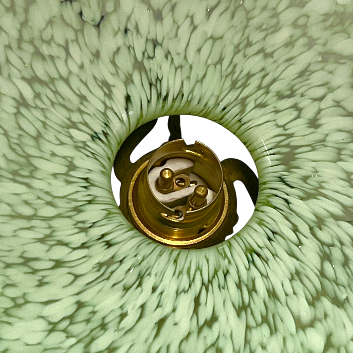Close-up of green glass patterned lam shade inner with a brass bulb holder