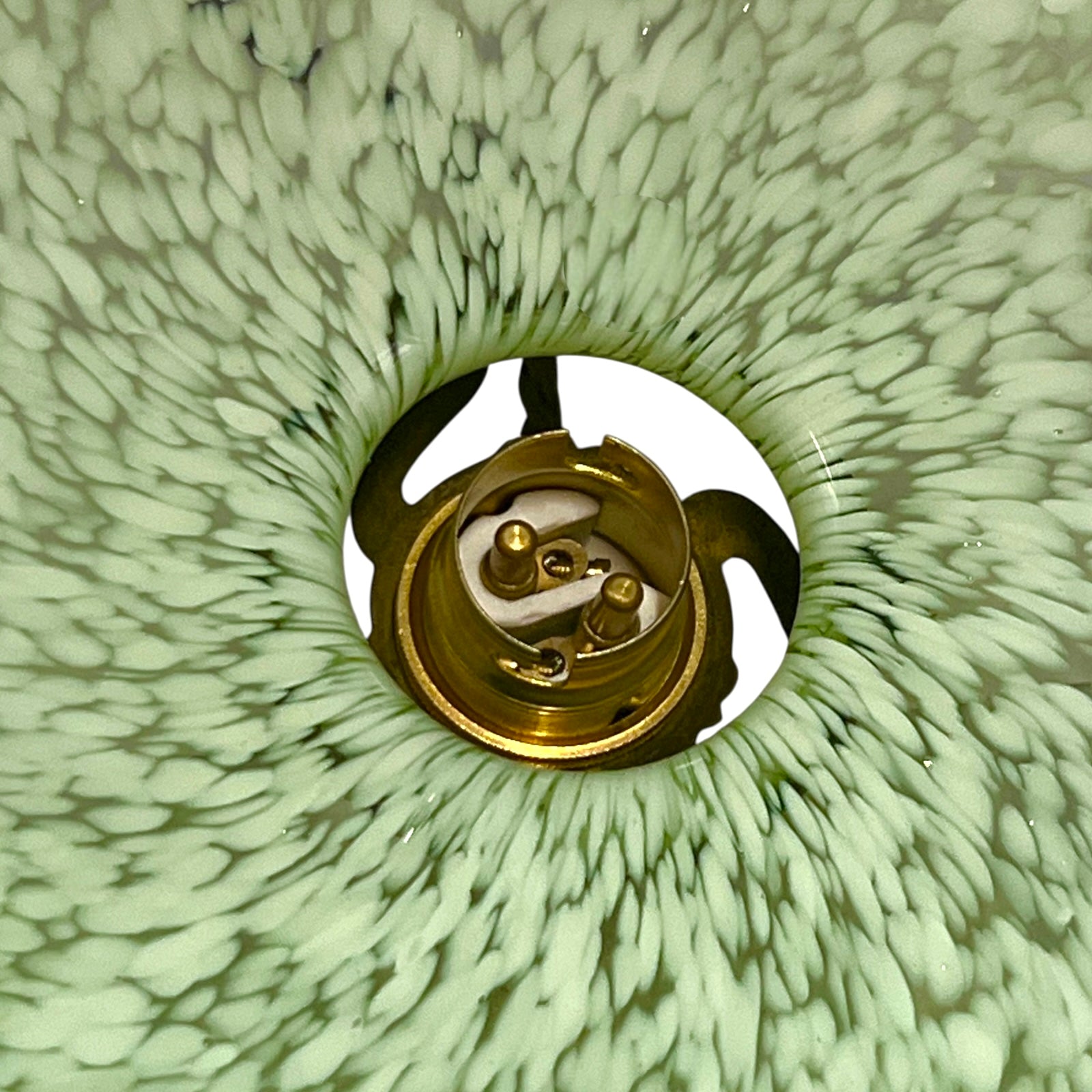 Close-up of green glass patterned lam shade inner with a brass bulb holder