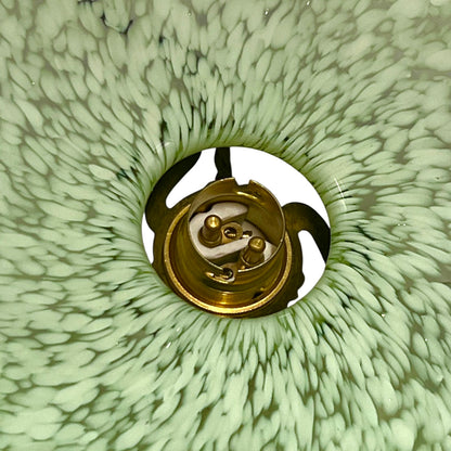 Close-up of green glass patterned lam shade inner with a brass bulb holder