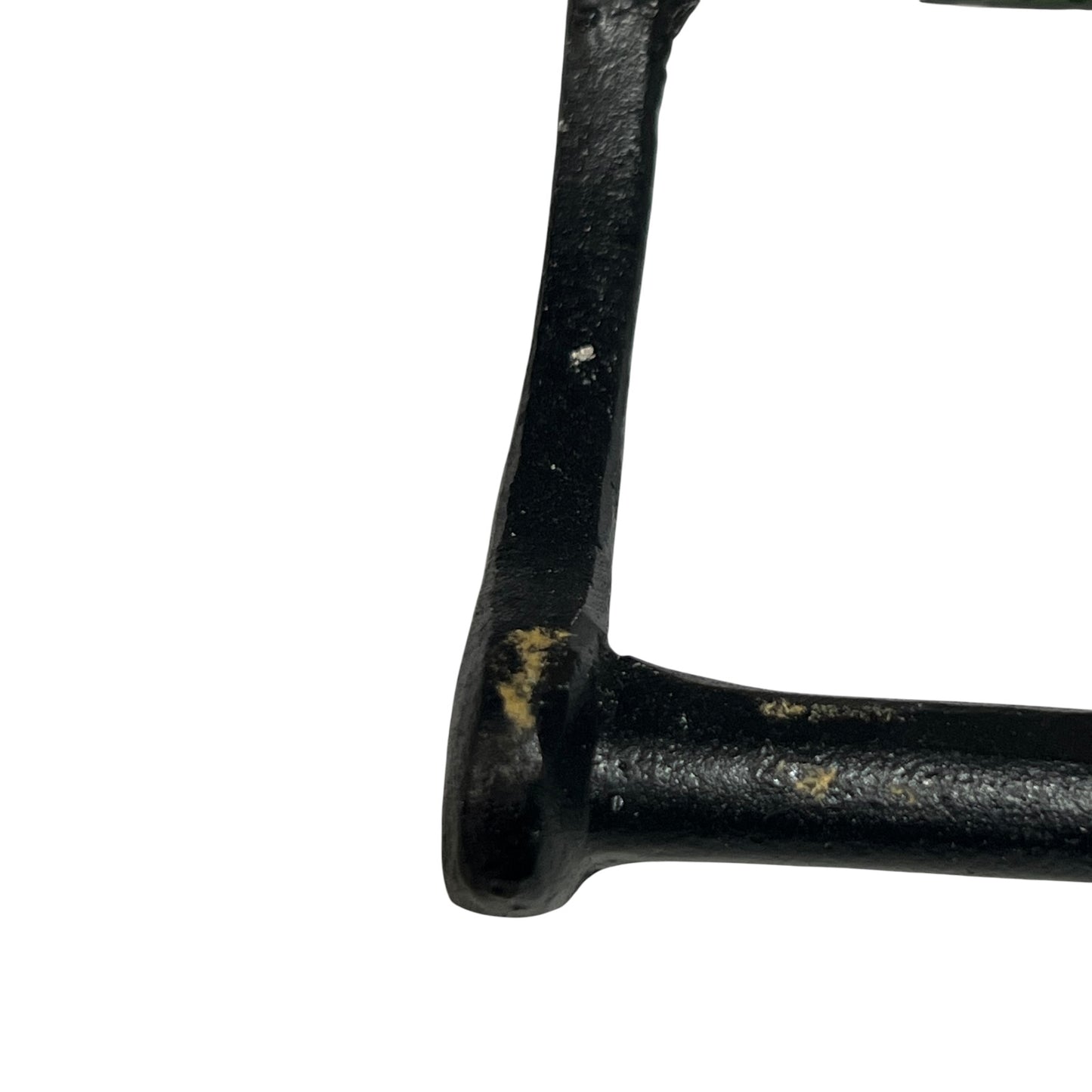 Close-up of a black cast iron frame corner with some weathered rust and paint chipping, isolated on a white background.