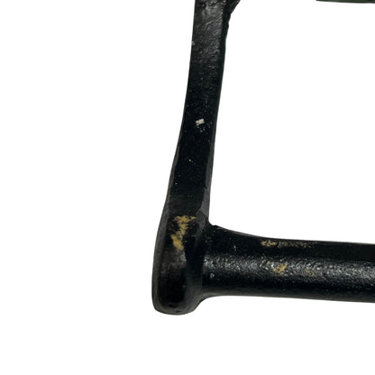 Close-up of a black cast iron frame corner with some weathered rust and paint chipping, isolated on a white background.
