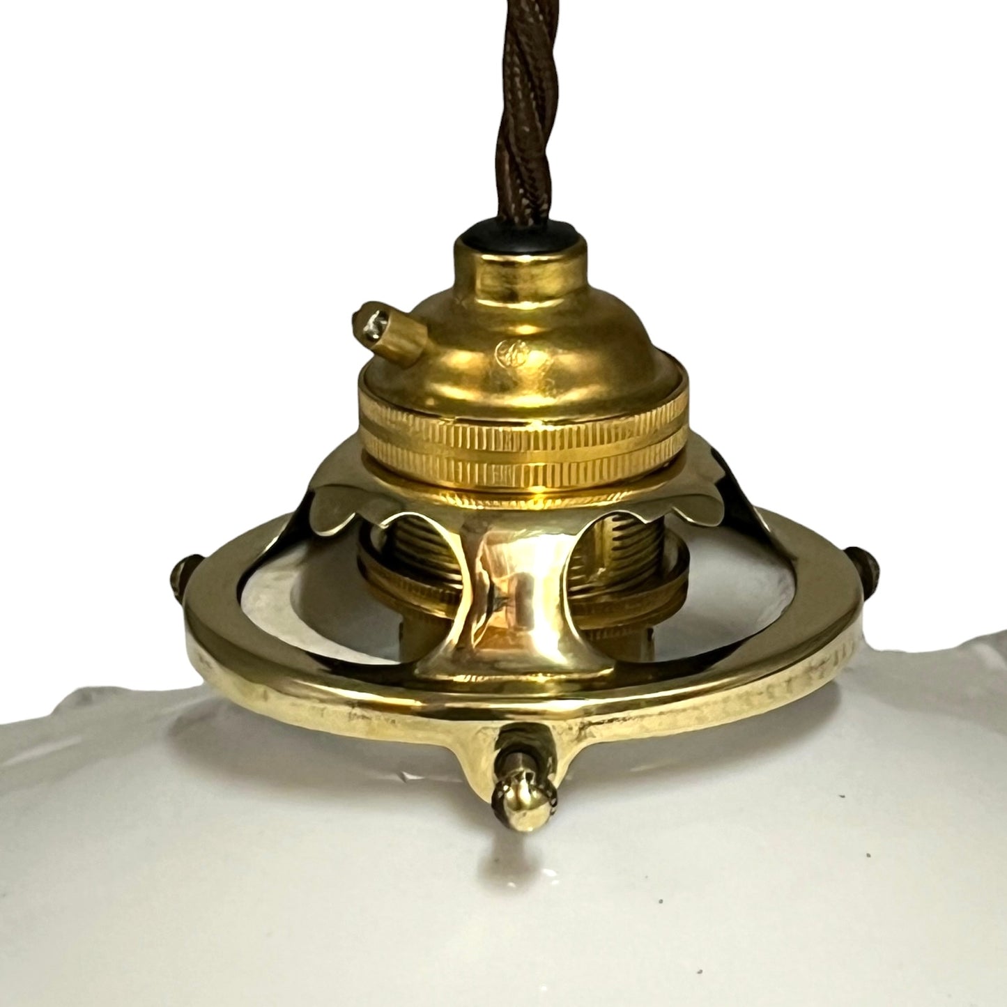 A close-up of a vintage brass ceiling light fixture canopy with a dark brown woven cord, set against a white background.