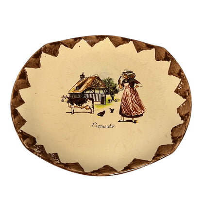 Decorative plate with a rural scene and 'Normandie' text on a white background