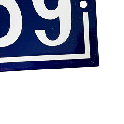 Close-up of a dark blue rectangular sign or plaque with large white numerals and a white border, shown against a white background.