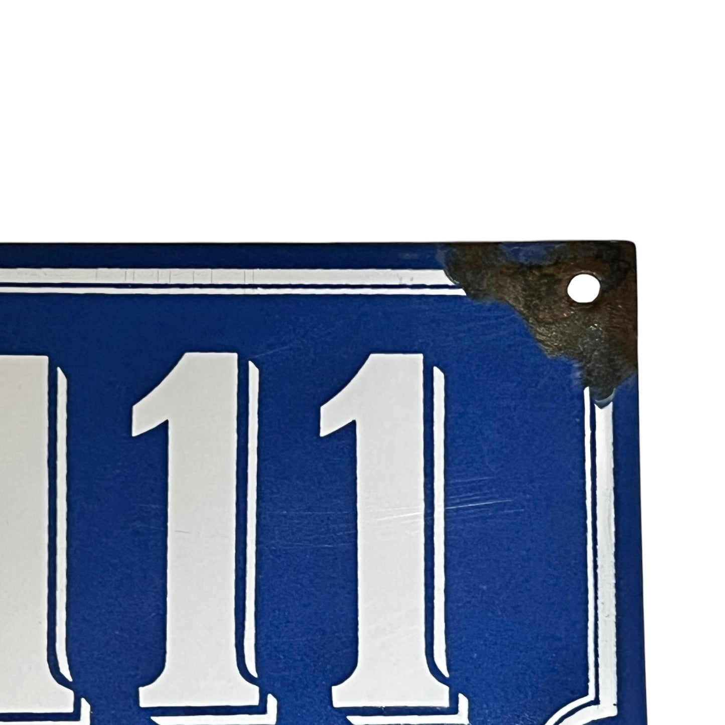 Close up of a blue French metal house number plate with white numbers '111' on a white background