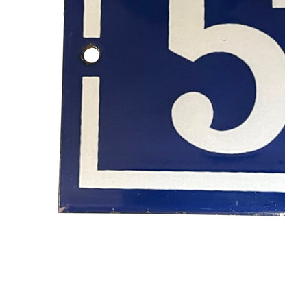 A close-up of a blue and white house number sign showing the number 51 with a mounting hole on the left.