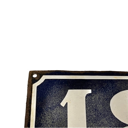 Close-up of a vintage-style metal sign showing part of a white numeral '1' on a dark blue background with a distressed brown border, isolated on a white background.