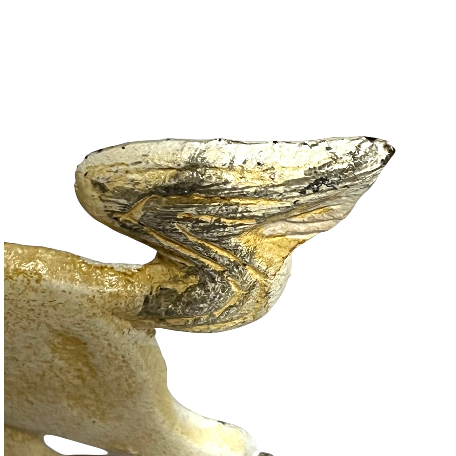 Close-up of a decorative object with a textured metallic gold and silver wing-like top and a cream-colored base, isolated on a white background.