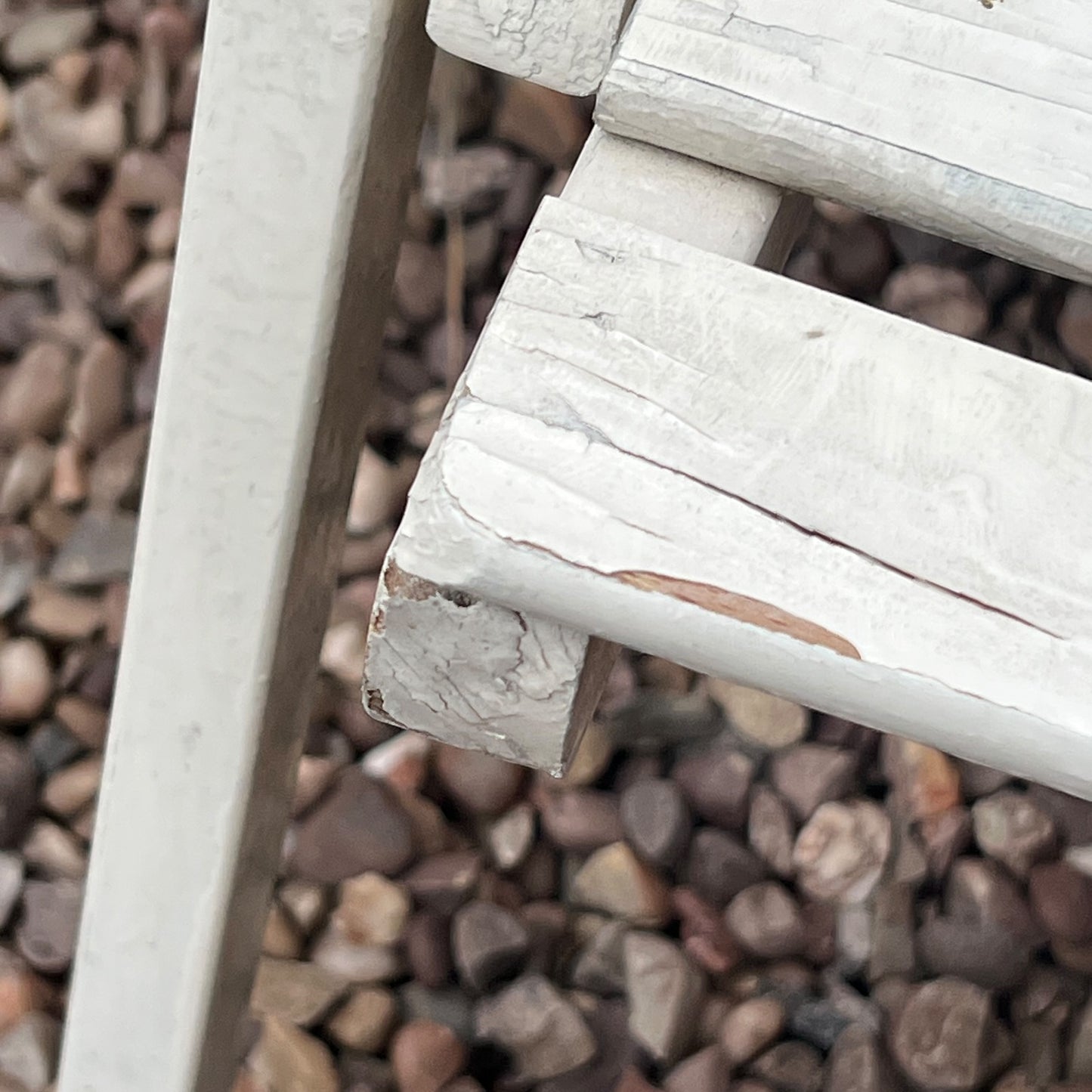 A close-up view of a painted wooden slatted garden chair set amidst a lush garden backdrop.