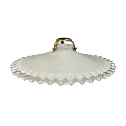 A vintage white milk glass lamp shade with a scalloped, fluted edge and a small gold metal handle, shown against a plain white background.