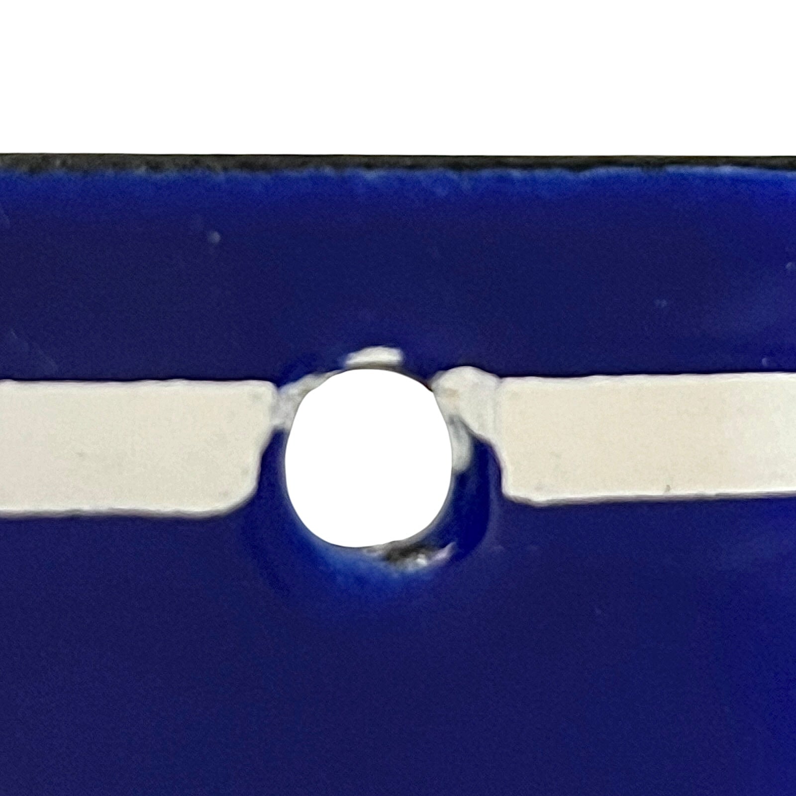 Close-up of a glossy dark blue object with a central circular cutout and a horizontal white strip running through the middle.