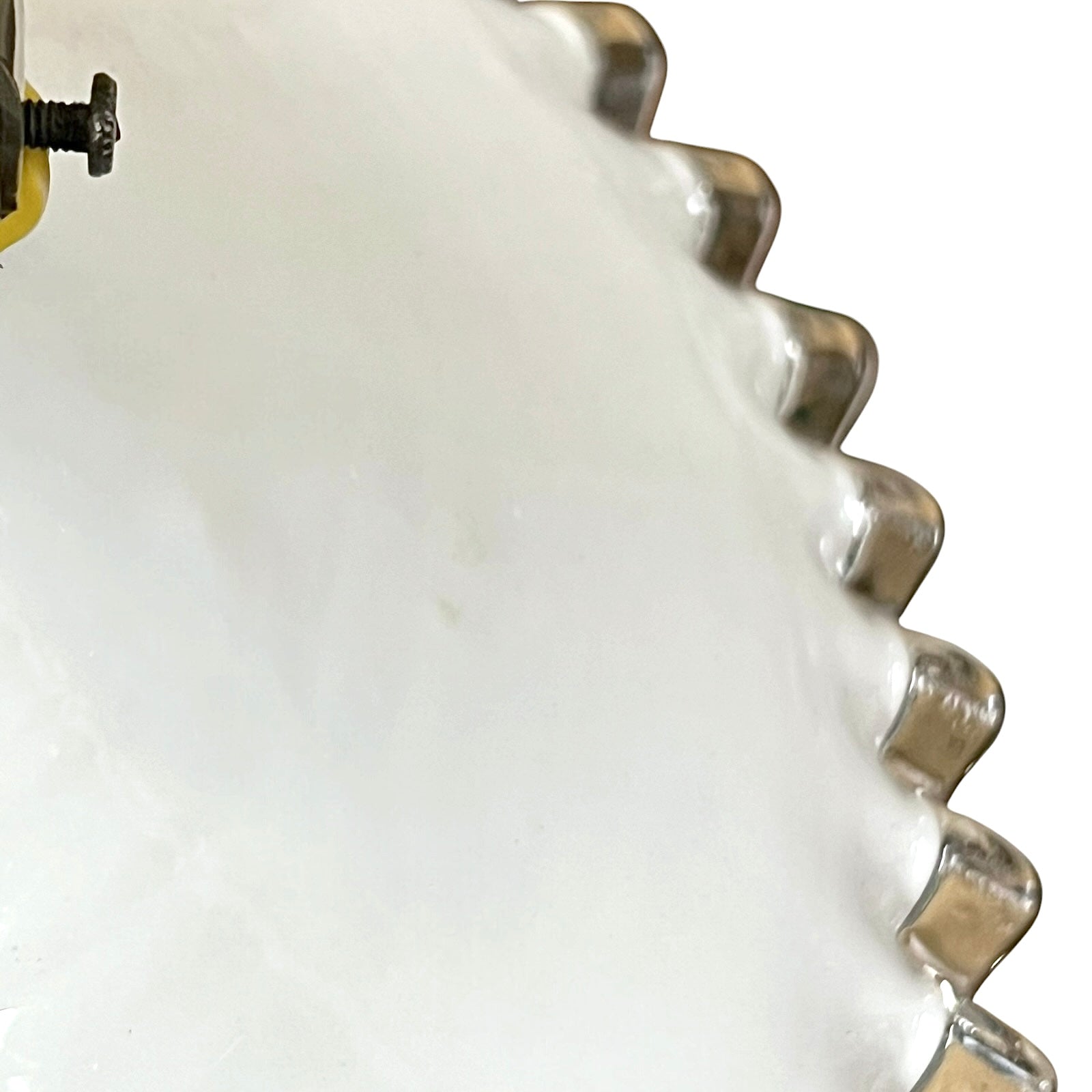 Close-up of a white glass lampshade with decorative edge on a white background