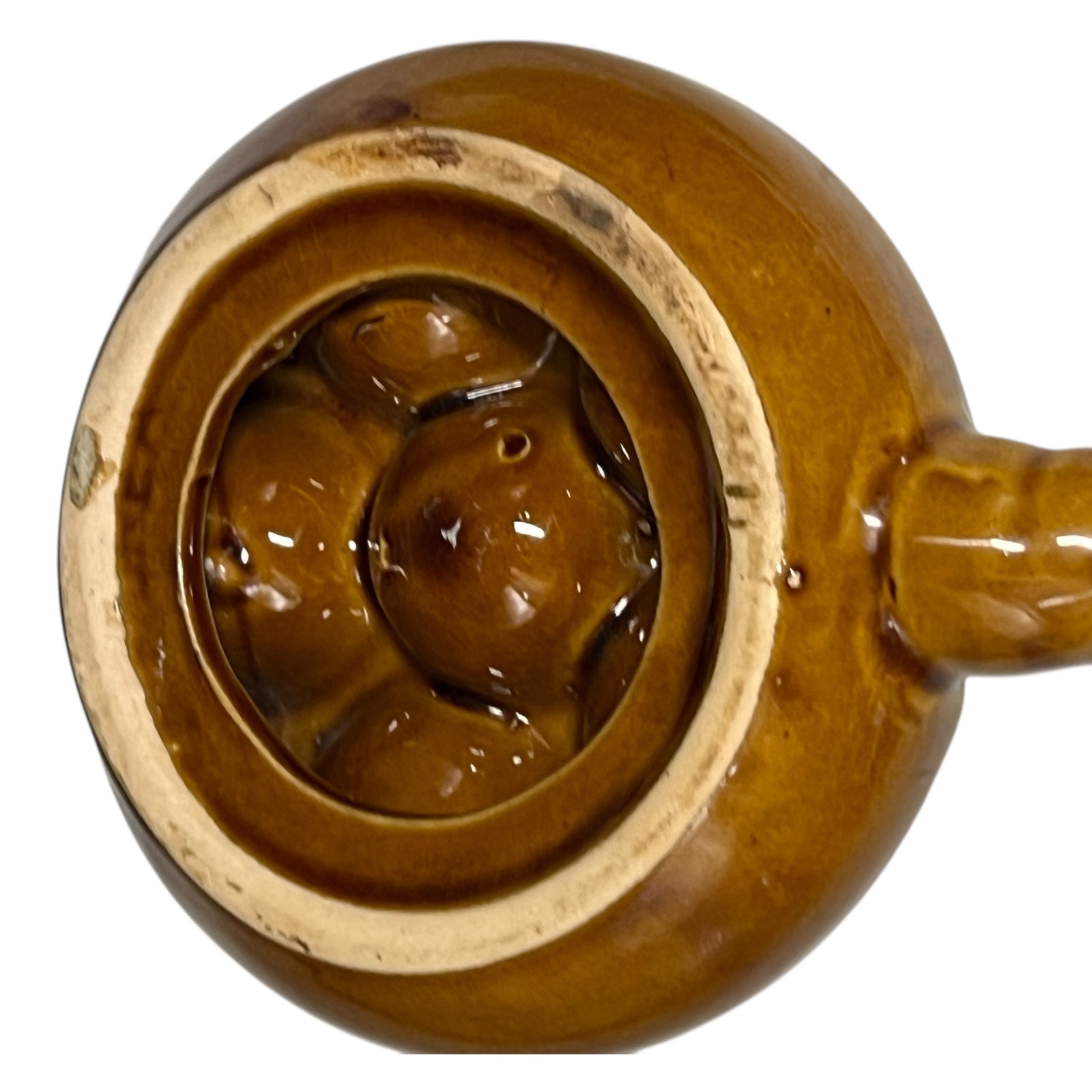 close up of a French brown ceramic escargots pot underside with multiple compartments on a white background