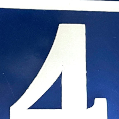 Close view of a vintage French enamel door number against a white background.