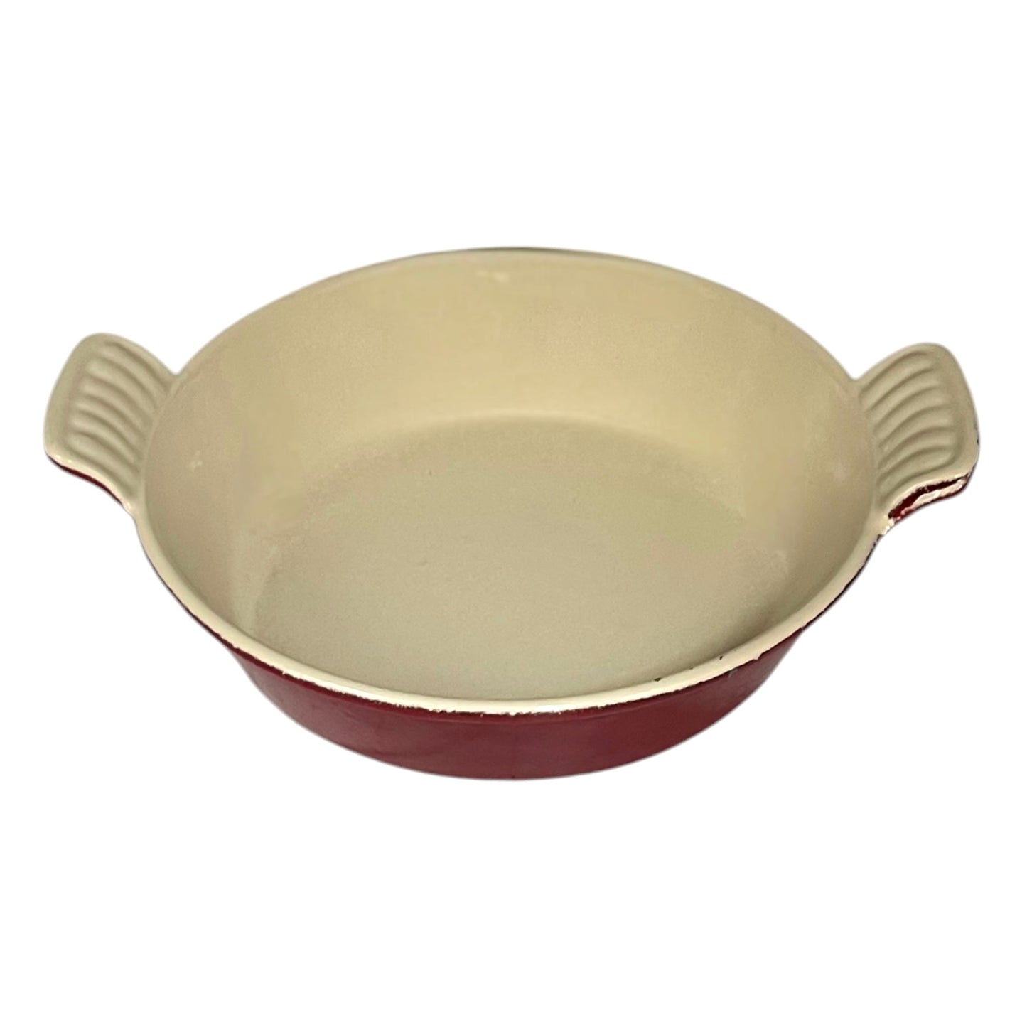 A round enameled cast iron casserole dish with a cream-colored interior and a dark red exterior, featuring two ribbed side handles.