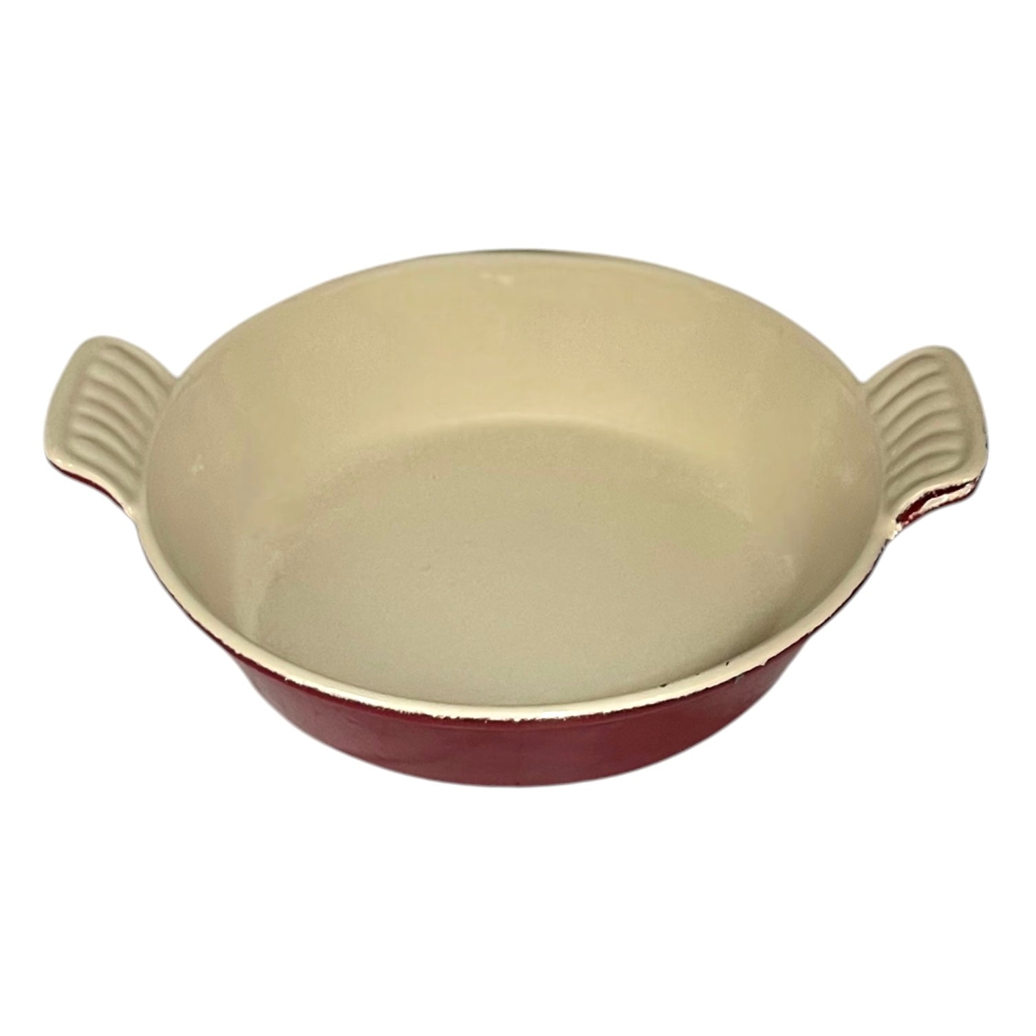 A round enameled cast iron casserole dish with a cream-colored interior and a dark red exterior, featuring two ribbed side handles.
