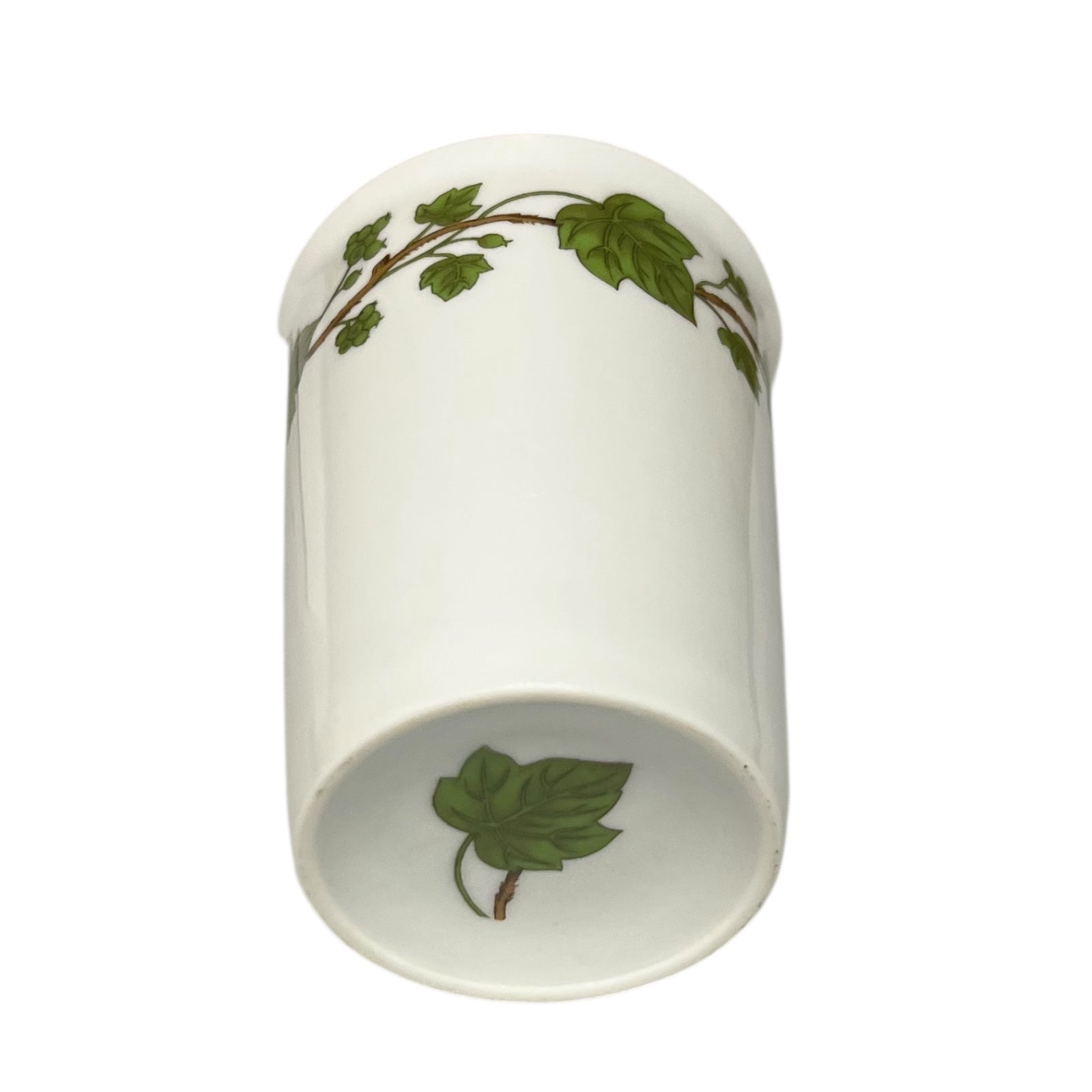 Porcelain bathroom tumbler  featuring green leaf patterns on a white background