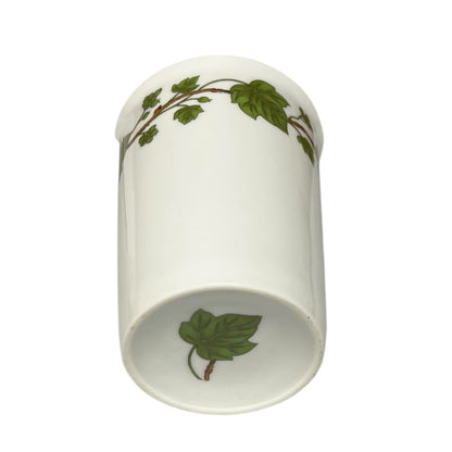Porcelain bathroom tumbler  featuring green leaf patterns on a white background