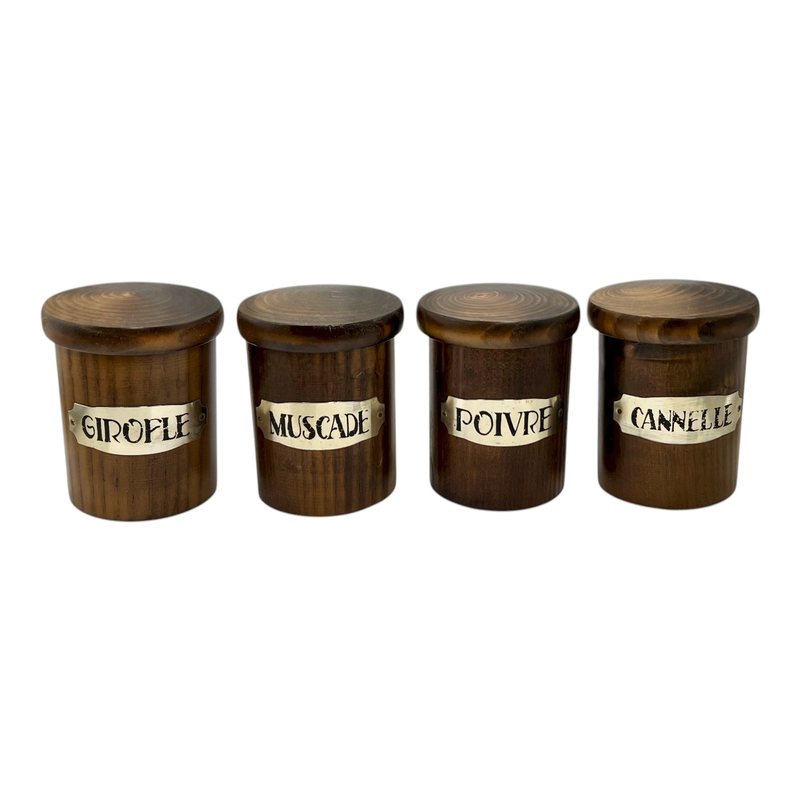 Four wooden spice jars with labels on a white background