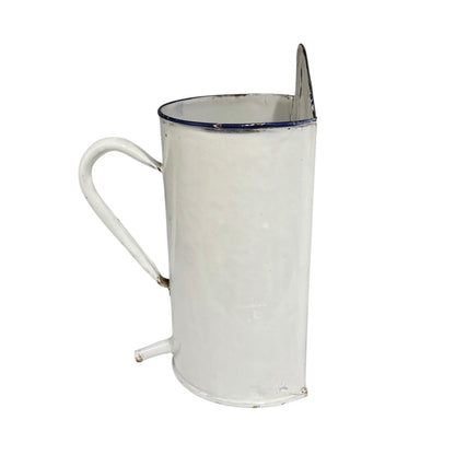 A vintage white enamel pot with a blue rim, a curved handle, and a small spout, shown against a plain white background.