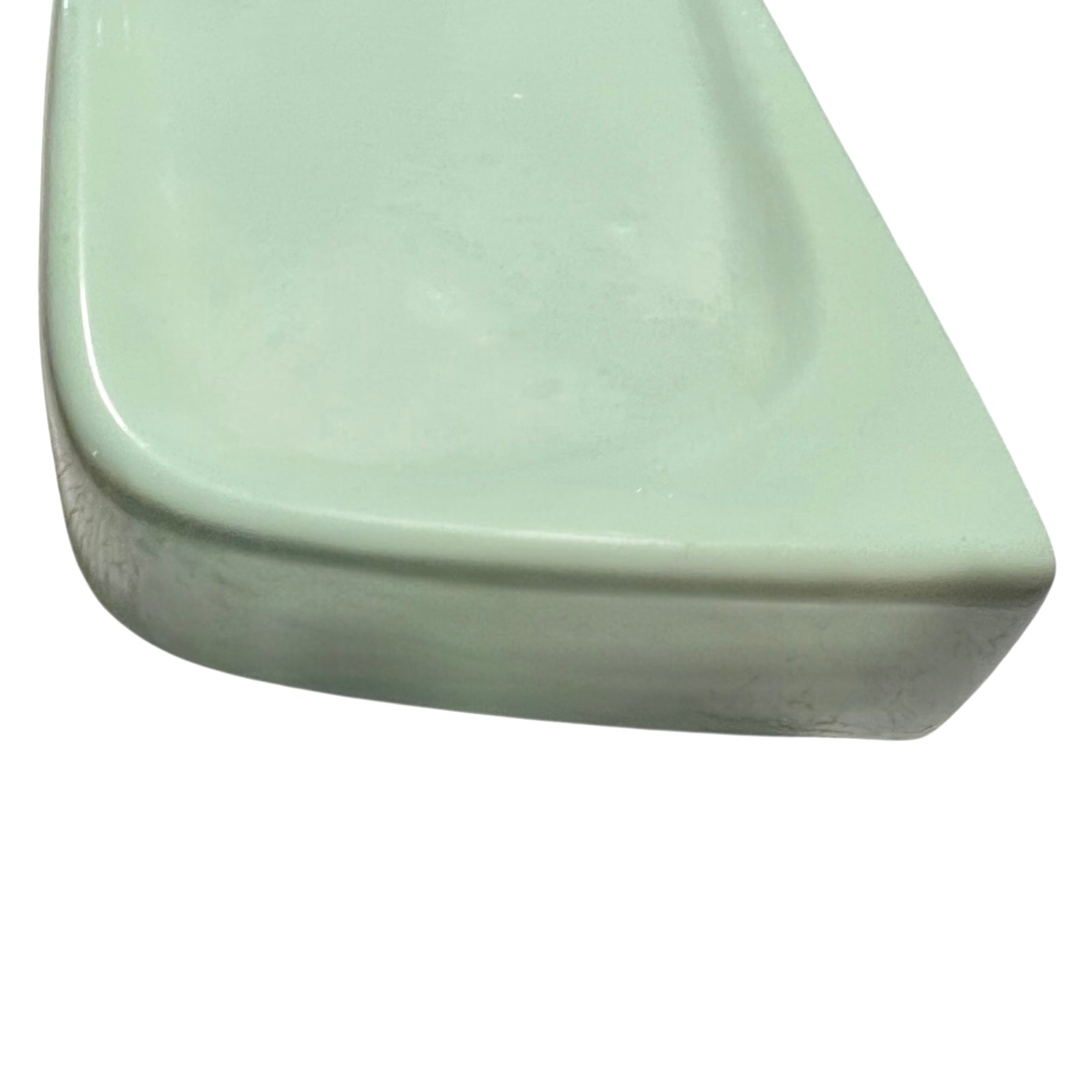 close up of pale green ceramic shelf on a white background