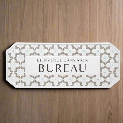 Decorative sign with floral pattern and text 'BIENVENUE DANS MON BUREAU' on a wooden background