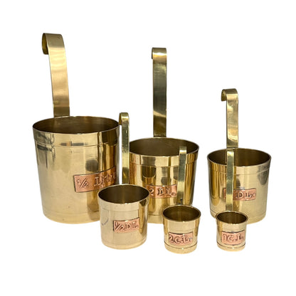Set of brass measuring cups with handles on a white background