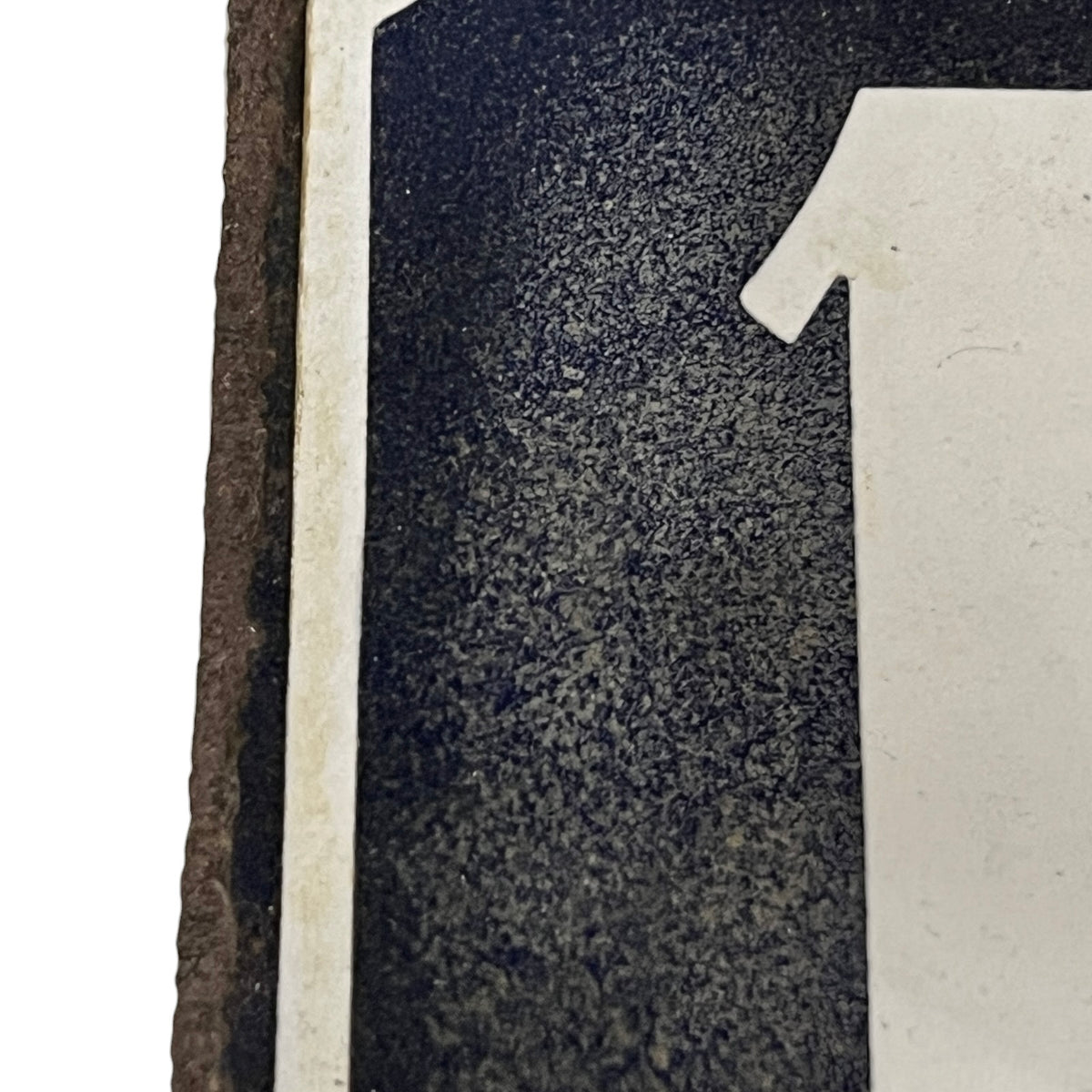 Close up of a blue enamel plaque with a white number 18 set on a white background 