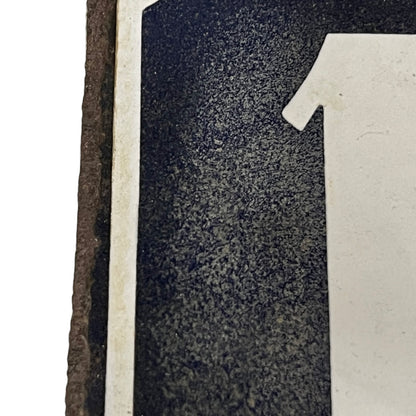 Close up of a blue enamel plaque with a white number 18 set on a white background 