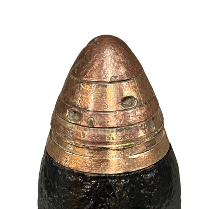 A close up of a WW1 18 pounder consisting of a brass shell, iron shrapnel and brass fuse on a white background 