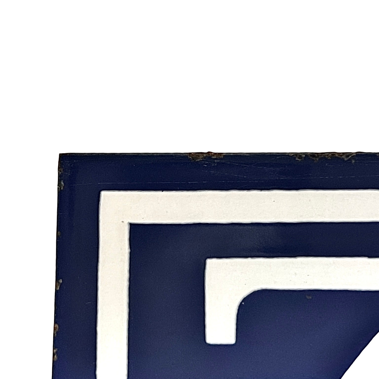 Close-up of a navy blue and white geometric wall art piece showing a corner with distressed edges on a white background.
