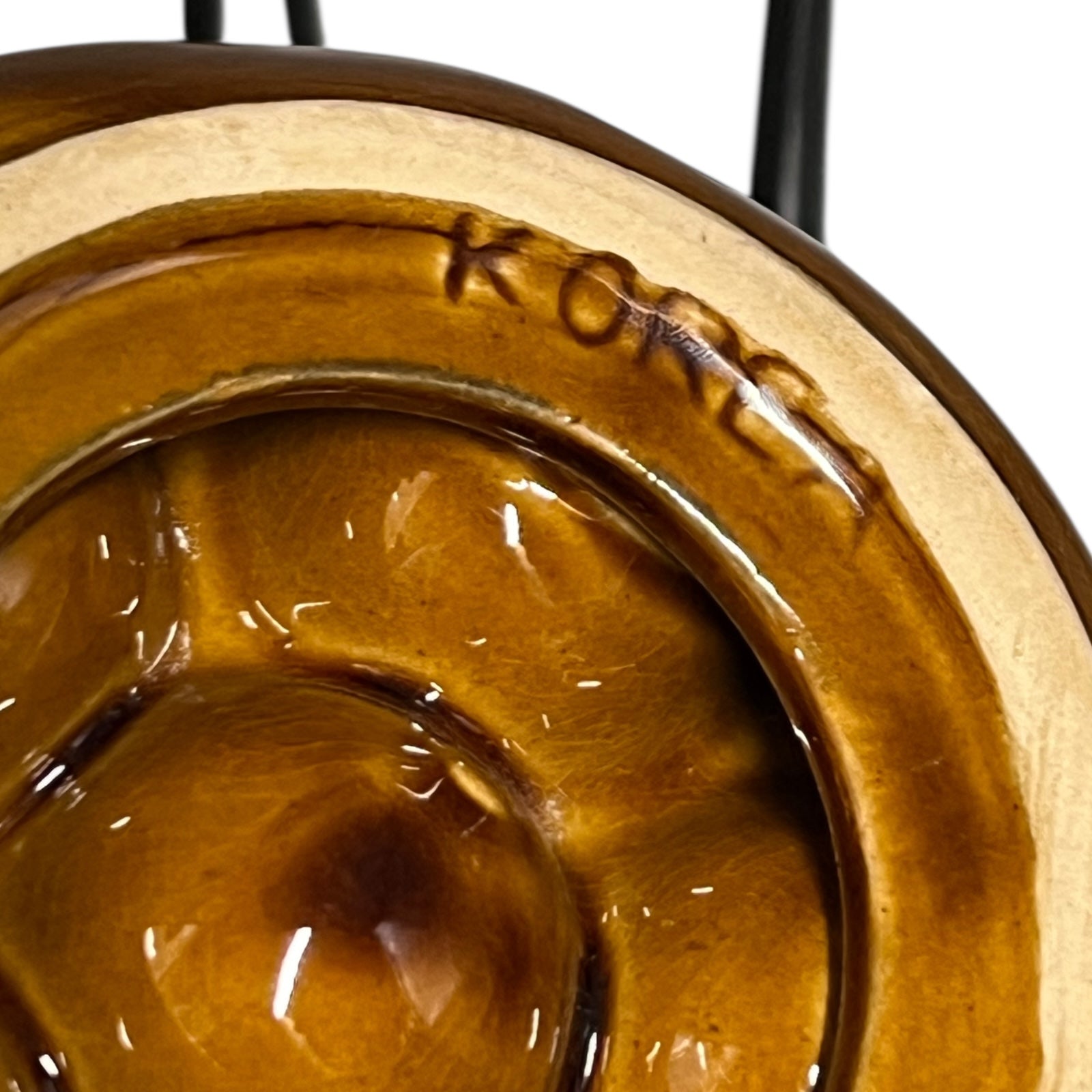 close up of a French brown ceramic escargots pot underside with multiple compartments on a white background