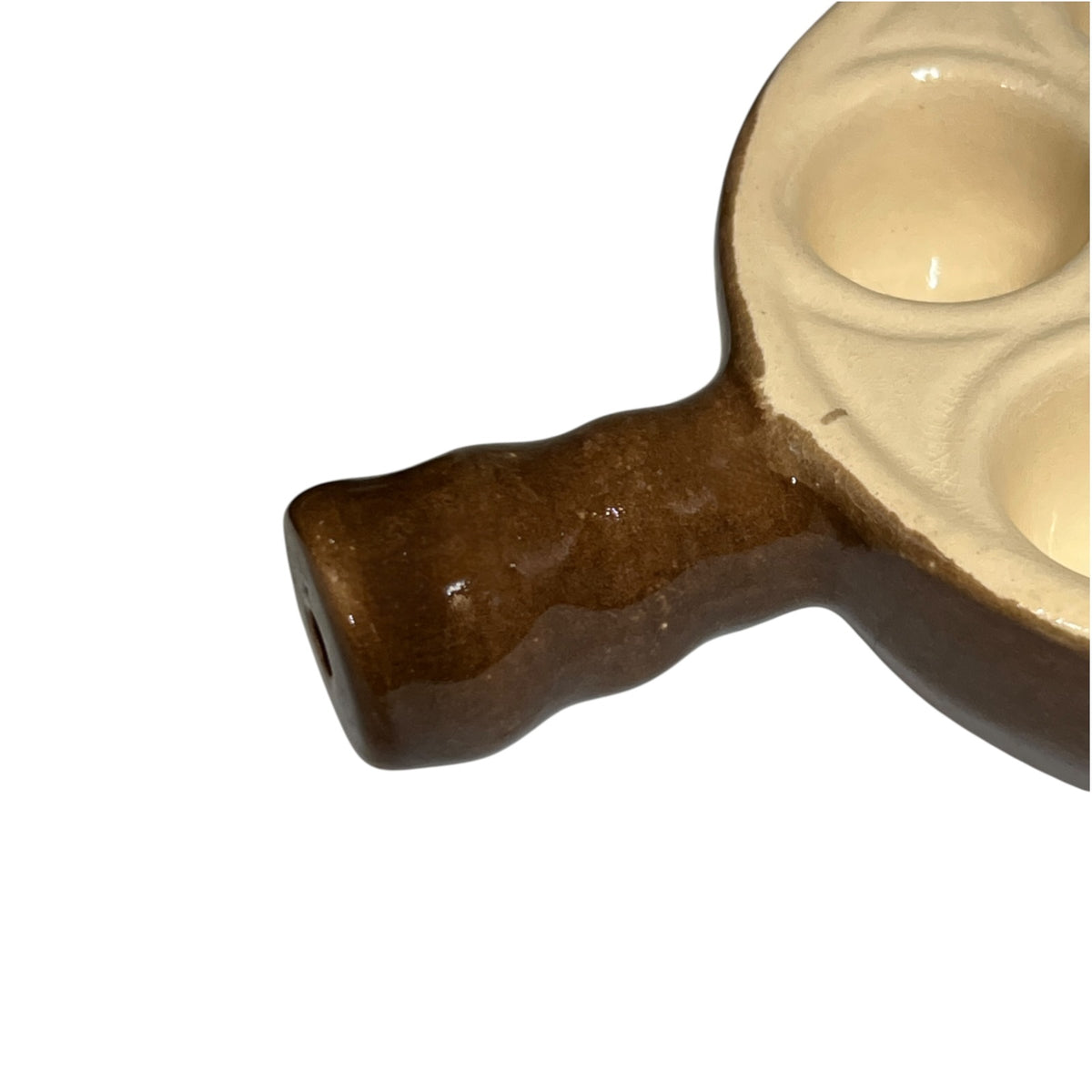 Close-up of a ceramic brown handle and cream-colored paint wells on a white background.