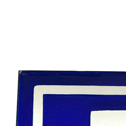 Close-up corner of a blue and white geometric graphic or sign with a thick white border and deep cobalt blue fill.