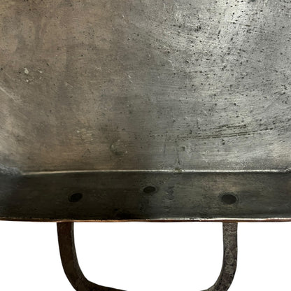 Close up of a copper roasting pan with a long handle on a white background